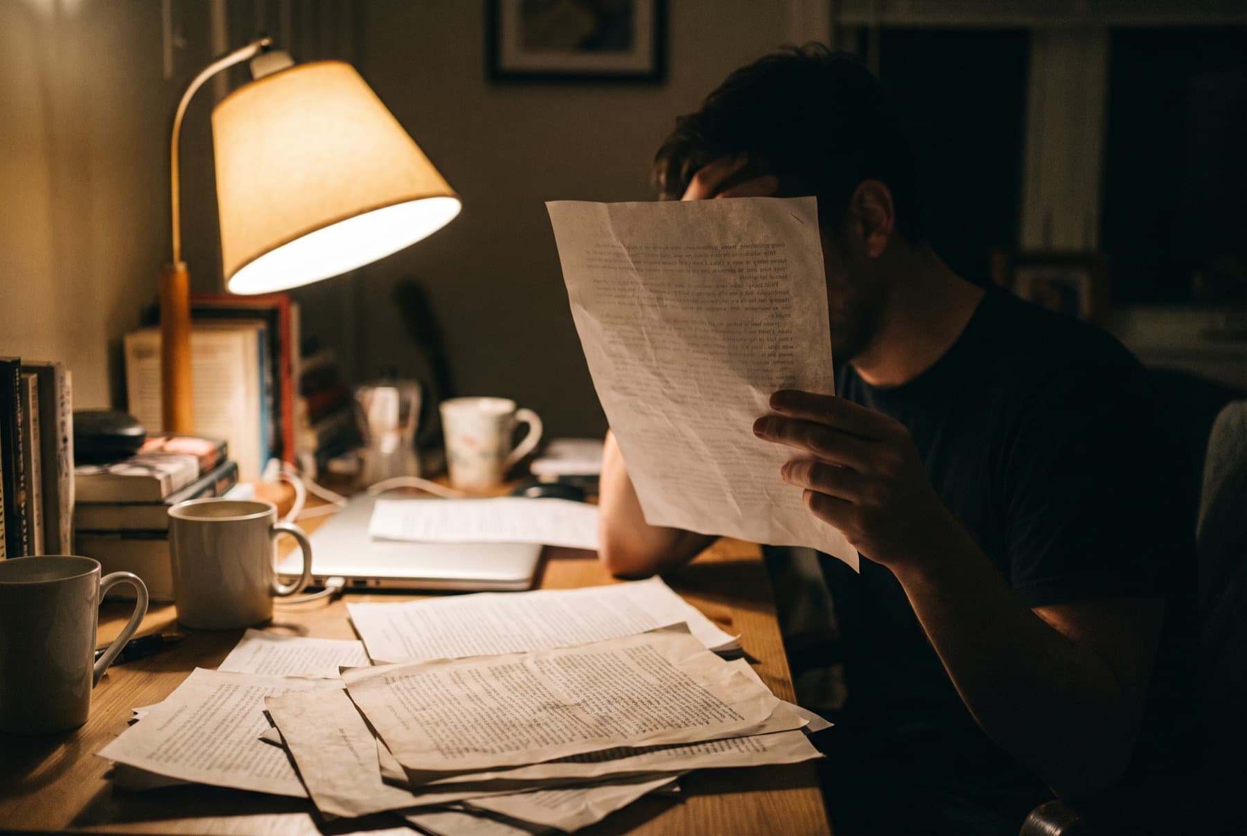 A person reading printed emails at a desk late at night