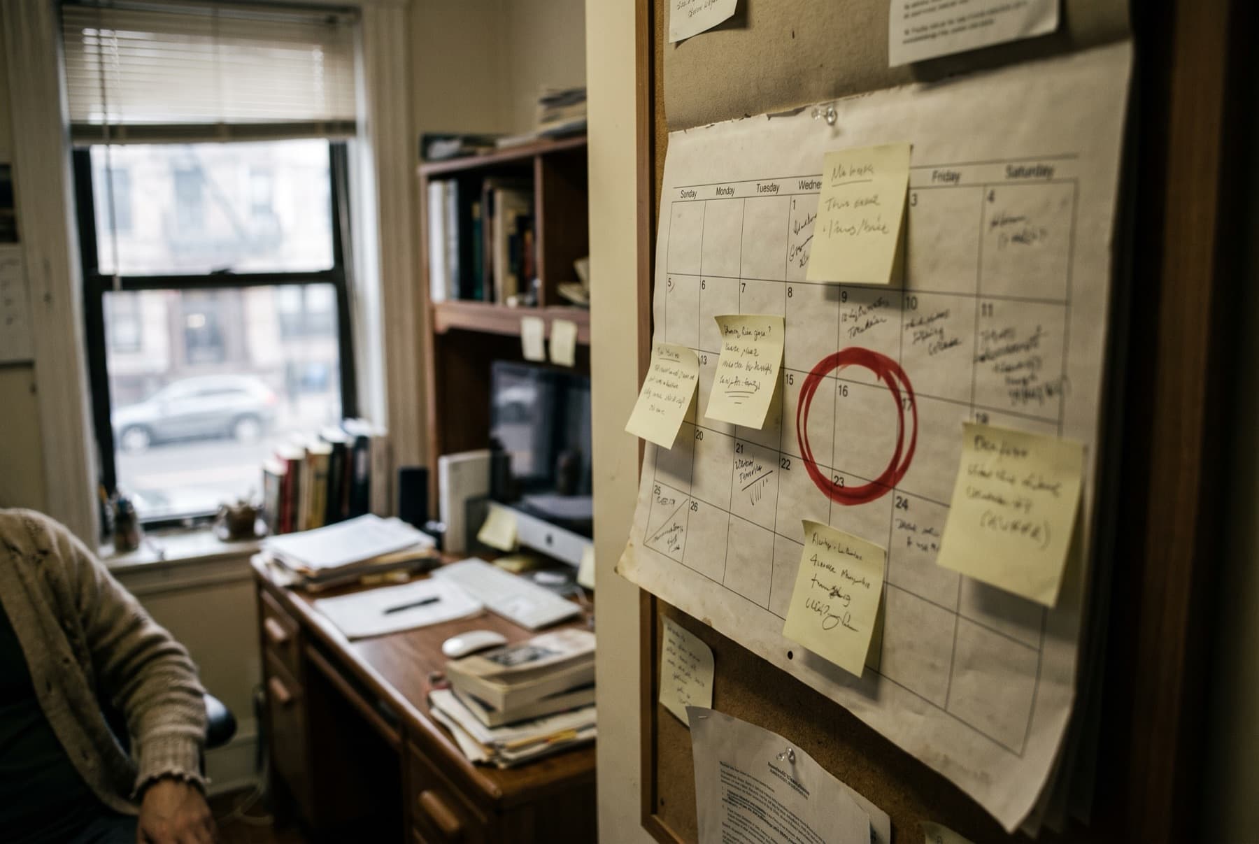 A paper wall calendar in a cluttered small office