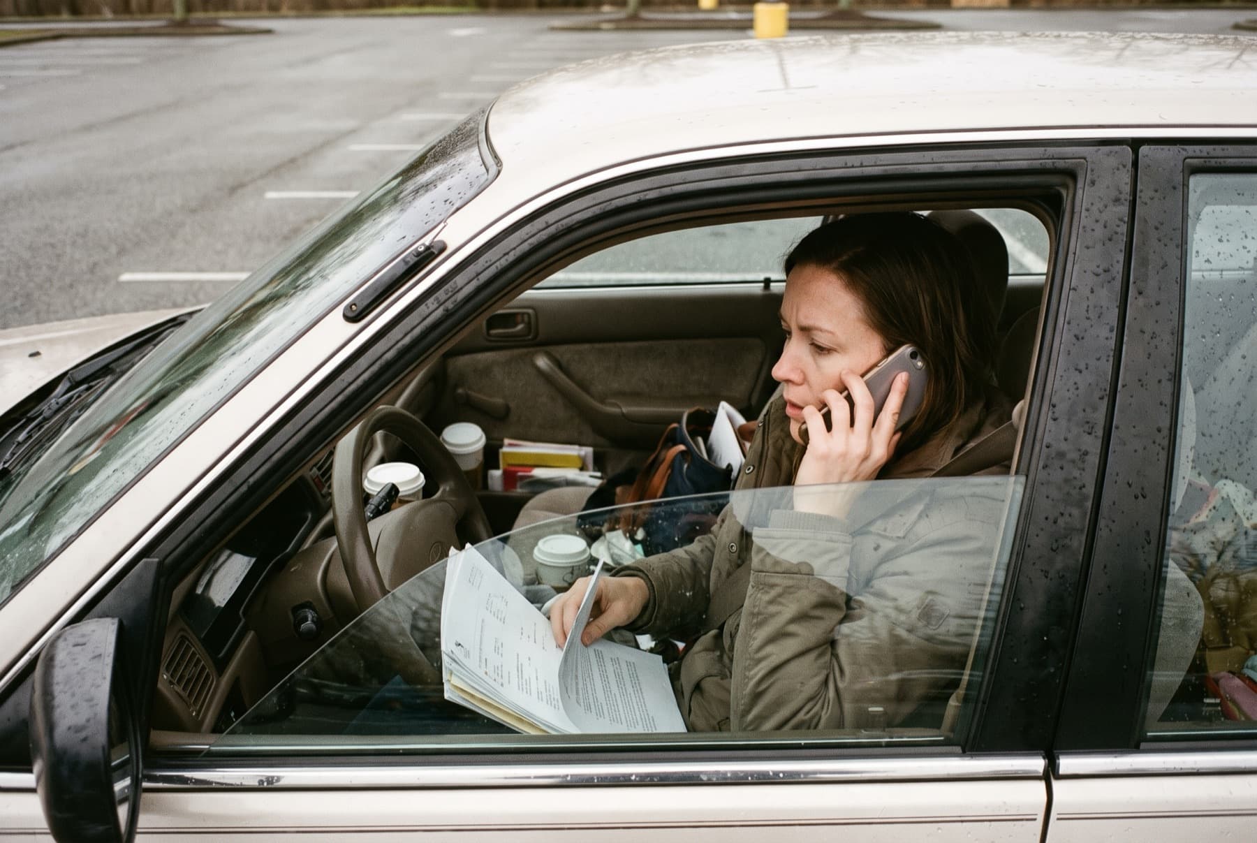 A woman in her thirties sitting in a car in a parking lot